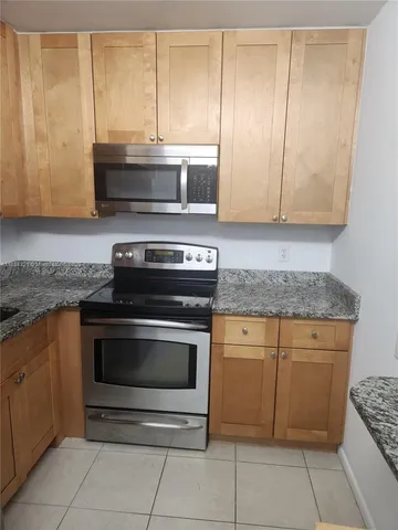 a kitchen with granite countertop a stove top oven microwave and cabinets