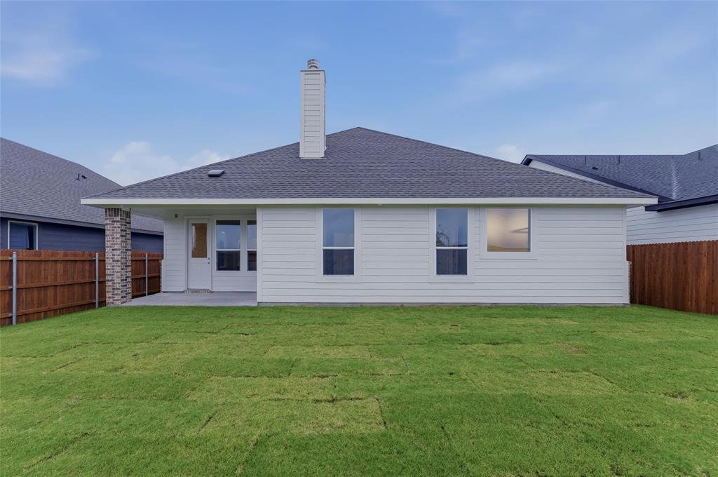 1329 Frio Drive Springtown, TX 76082 - Photo 23 of 25 White siding exterior featuring a covered patio, brick accent column, a single chimney, and a dark shingle roof