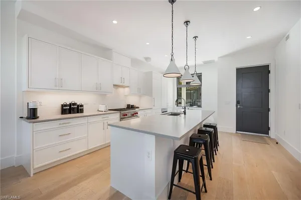 a kitchen with kitchen island a sink stove and white cabinets with wooden floor
