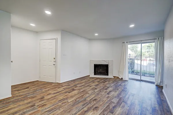 a view of empty room with wooden floor and fireplace