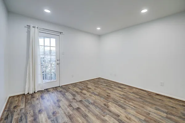 a view of an empty room with wooden floor and a window