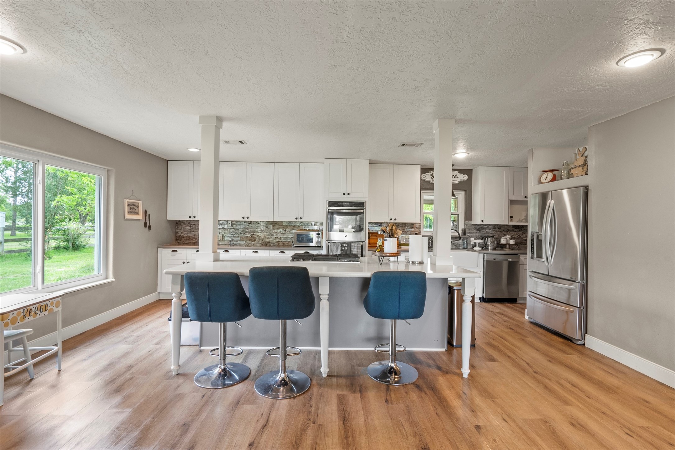 5211 Ghinaudo Road Hitchcock, TX 77563 - Photo 11 of 34 a kitchen with a dining table chairs refrigerator and cabinets