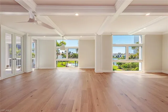 a view of an empty room with window and wooden floor