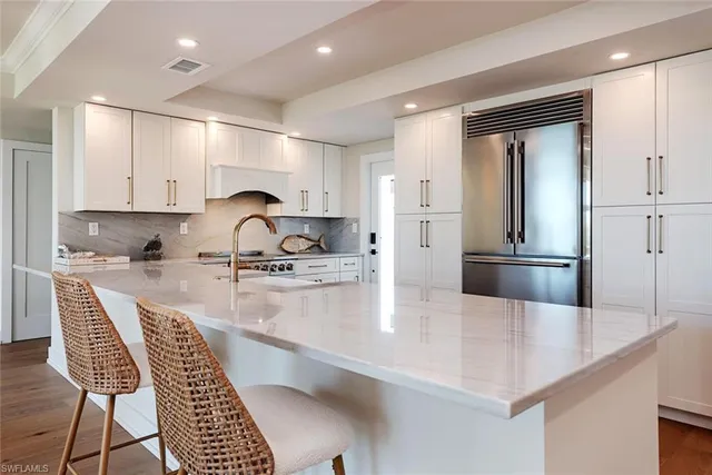 a kitchen with granite countertop a refrigerator a stove a sink a dining table and chairs