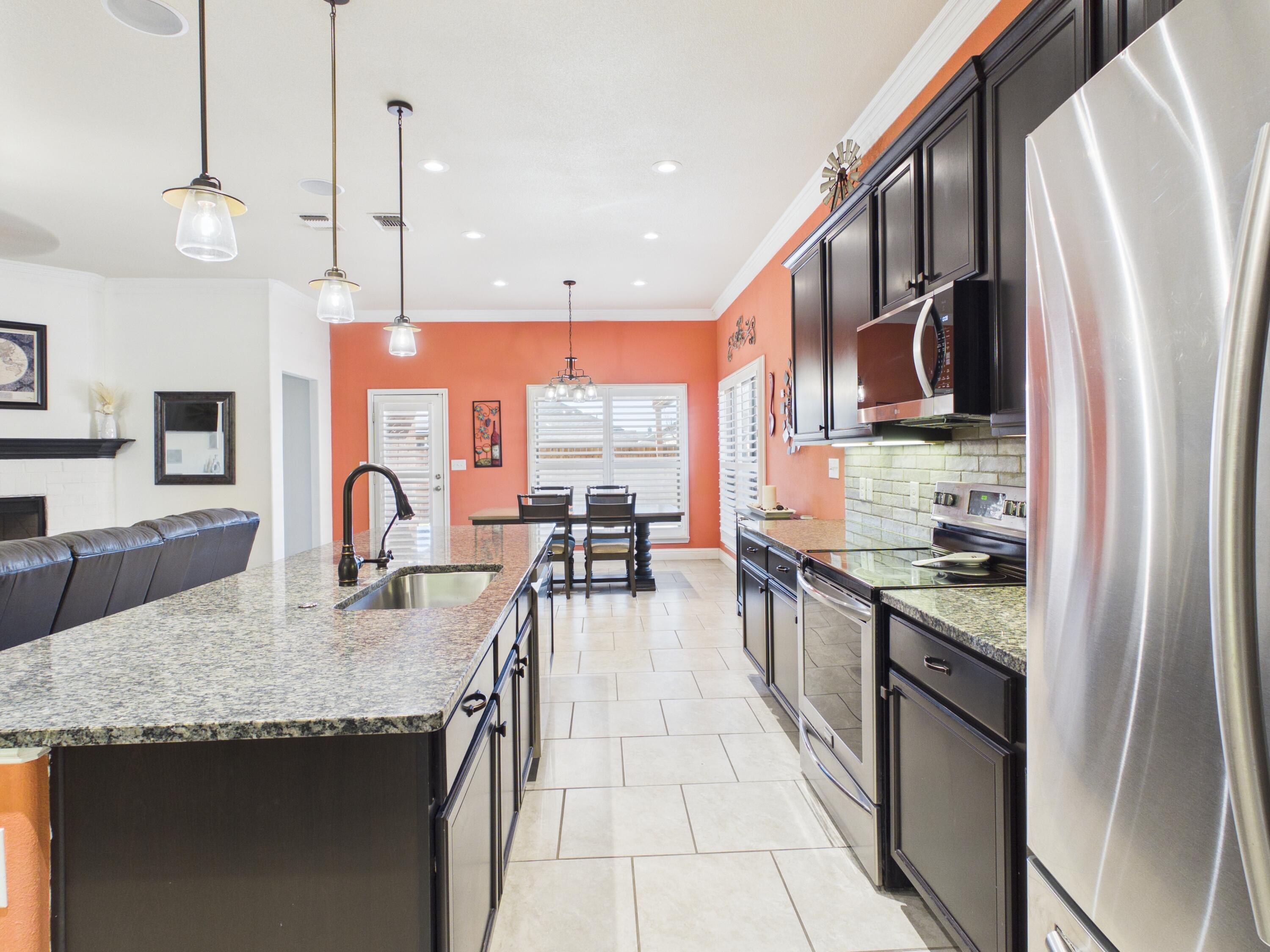 7101 94th Street Lubbock, TX 79424 - Photo 14 of 33 a kitchen with stainless steel appliances granite countertop a stove a sink and a refrigerator