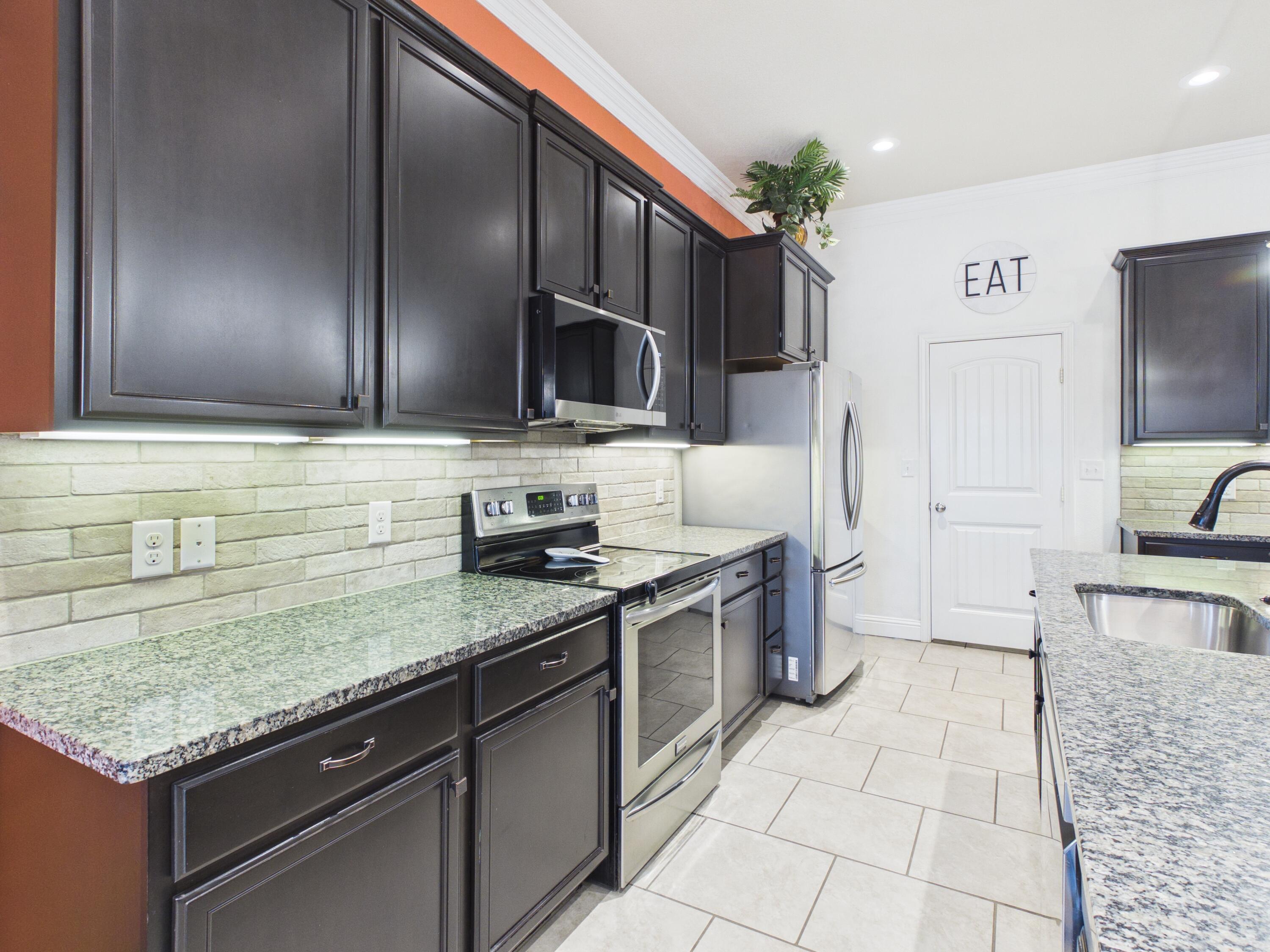 7101 94th Street Lubbock, TX 79424 - Photo 15 of 33 a kitchen with stainless steel appliances granite countertop a stove a sink and a microwave