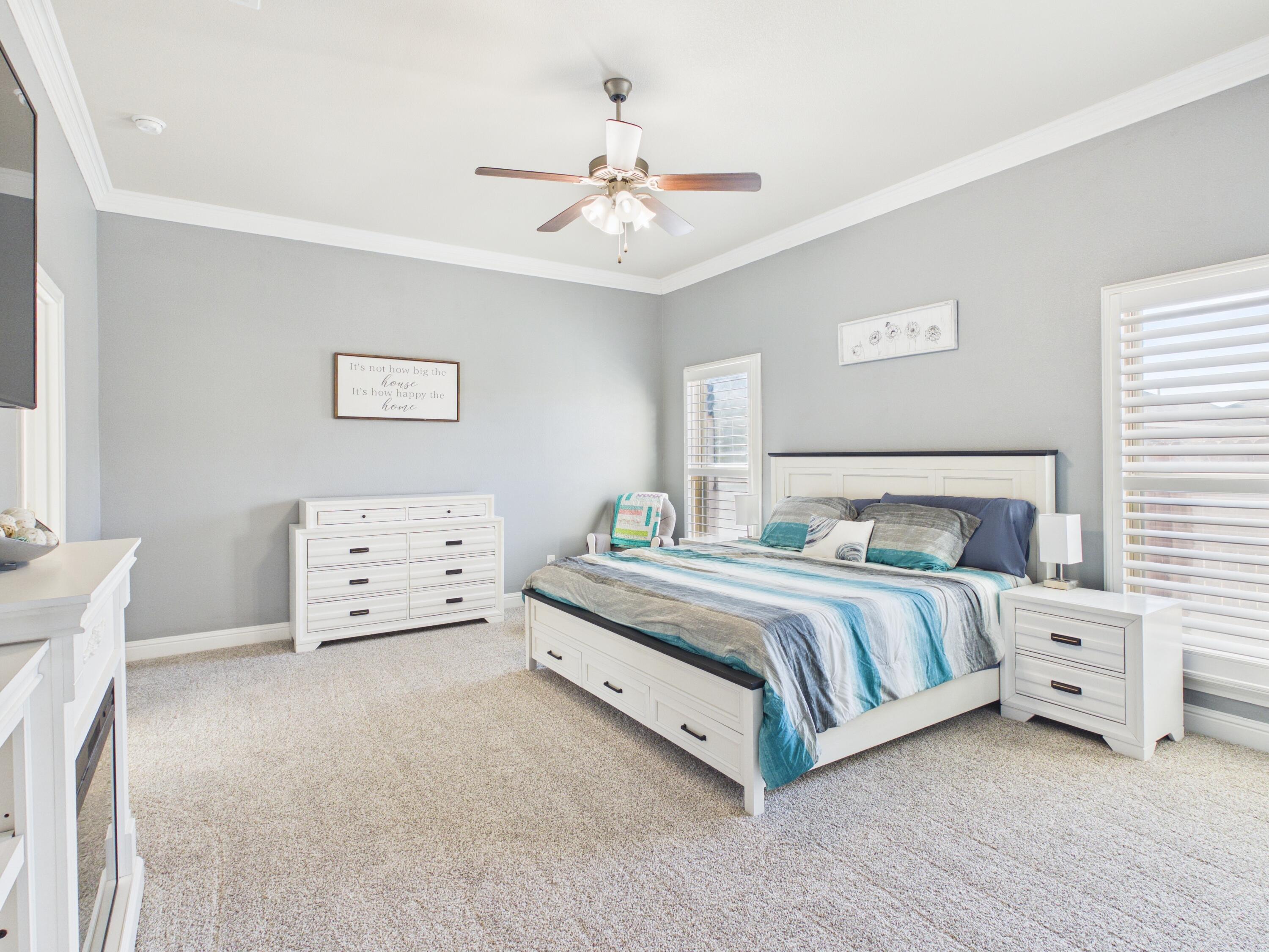 7101 94th Street Lubbock, TX 79424 - Photo 21 of 33 a spacious bedroom with a bed and a chandelier