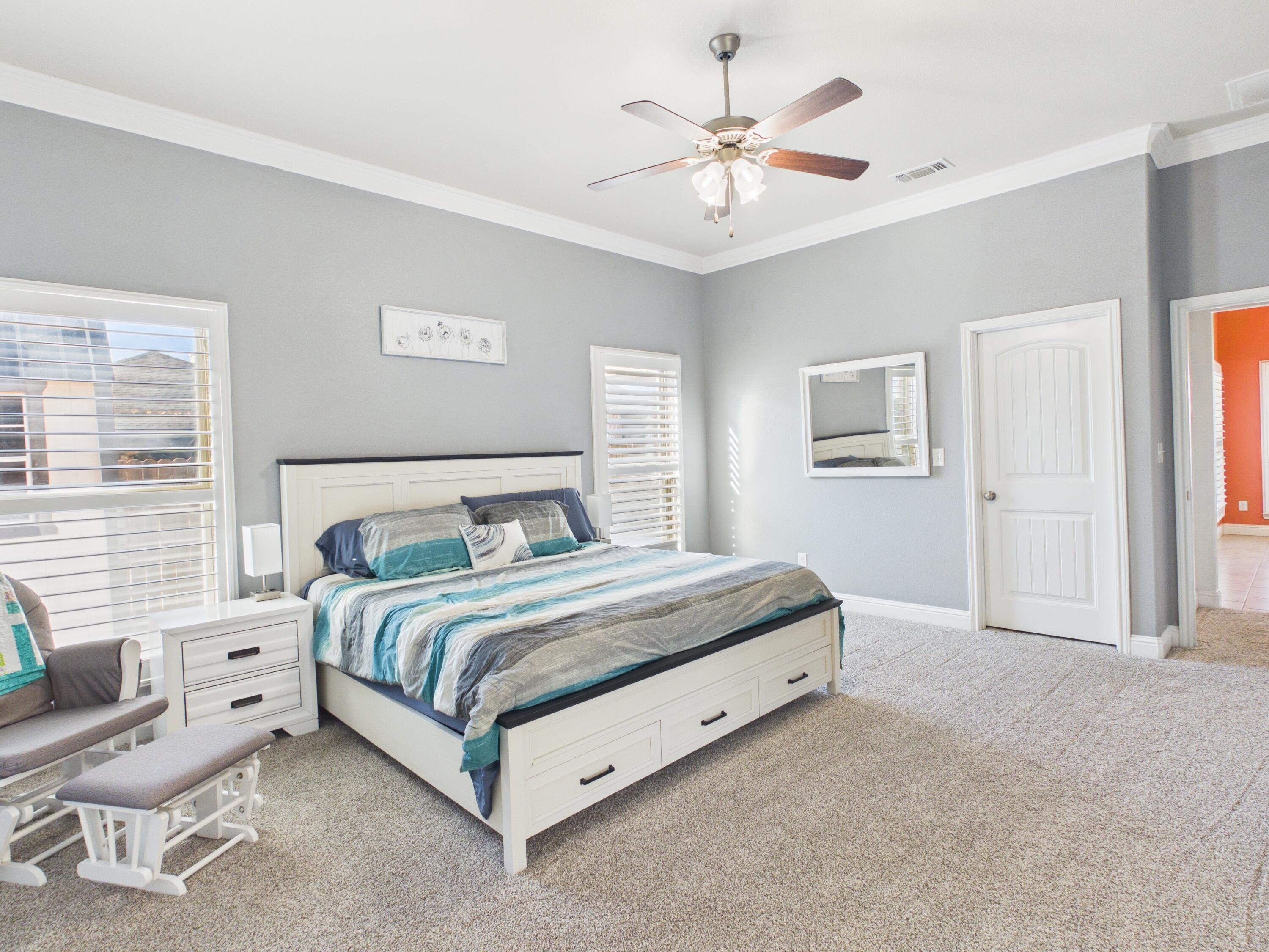 7101 94th Street Lubbock, TX 79424 - Photo 22 of 33 a spacious bedroom with a bed and a chandelier