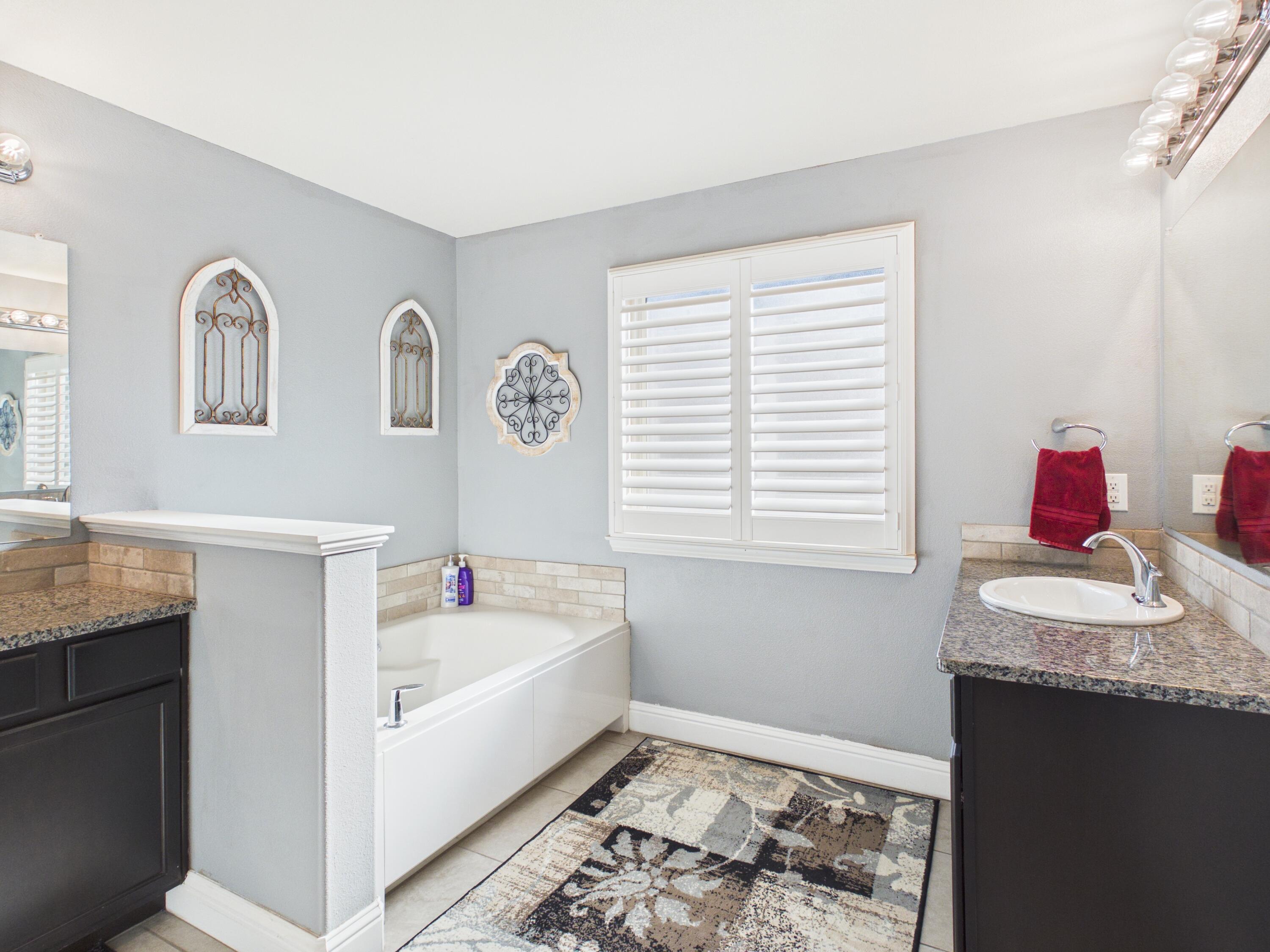 7101 94th Street Lubbock, TX 79424 - Photo 25 of 33 a bathroom with a granite countertop sink and a bathtub