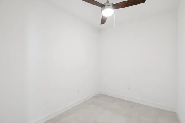 an empty room with a ceiling fan and carpet