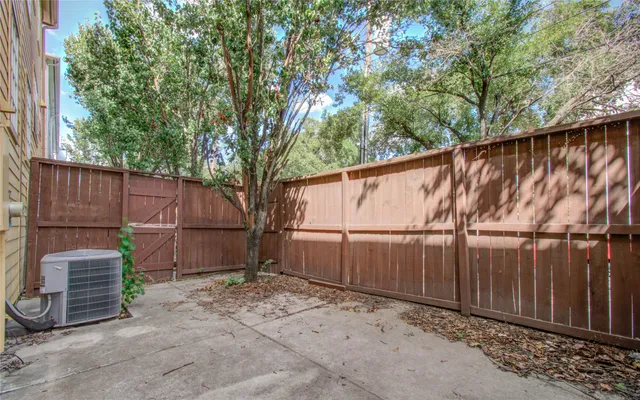 a backyard of a house with a tree and wooden fence