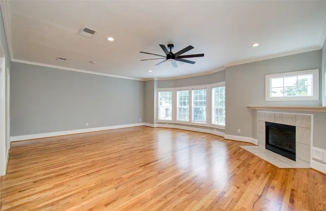 a view of an empty room with wooden floor and a fireplace