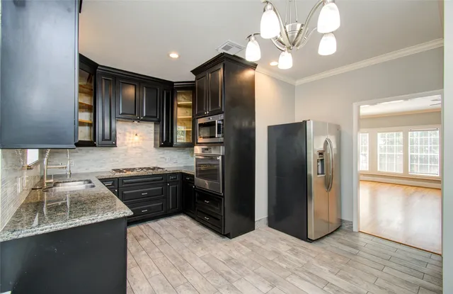 a kitchen with stainless steel appliances granite countertop a refrigerator a stove and a sink