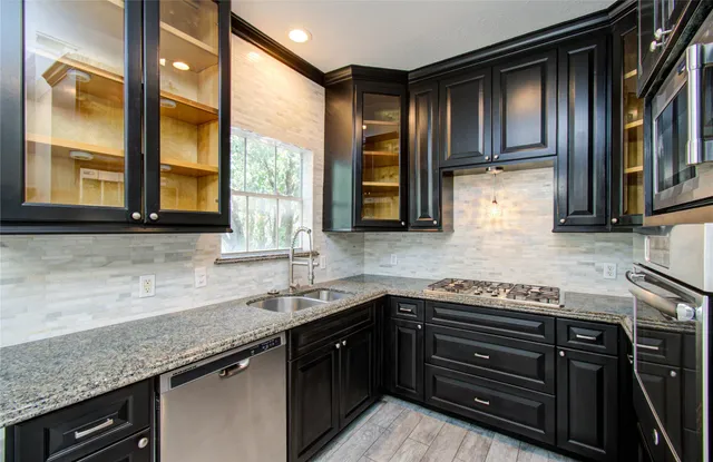 a kitchen with granite countertop stainless steel appliances a sink window and cabinets