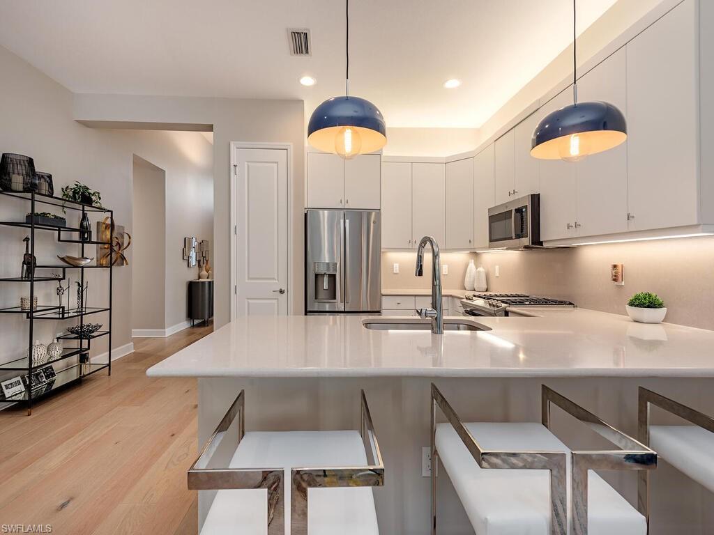 12456 Violet Lane Naples, FL 34120 - Photo 13 of 34 a kitchen with stainless steel appliances a dining table chairs and a refrigerator