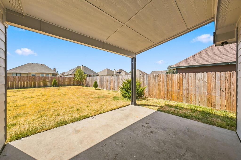 10409 Condor Loop Waco, TX 76708 - Photo 23 of 26 Covered patio with a concrete surface, a wood privacy fence, and an expansive lawn