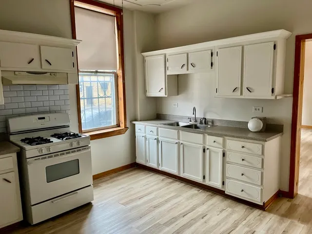 a kitchen with granite countertop white cabinets and white appliances