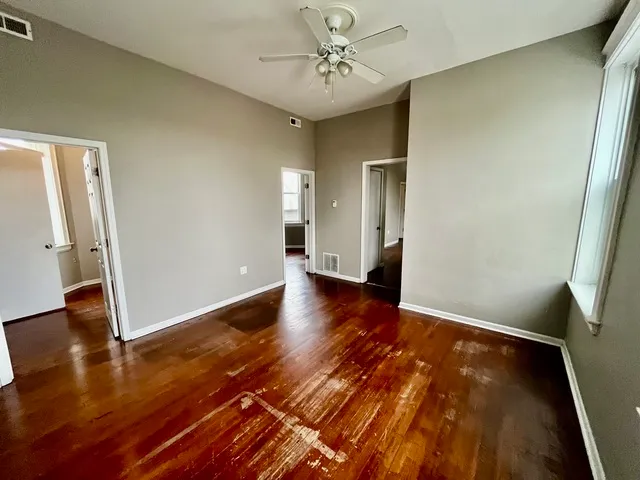 an empty room with wooden floor and a ceiling fan