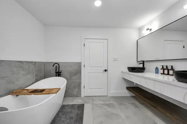 a bathroom with a tub a sink and mirror