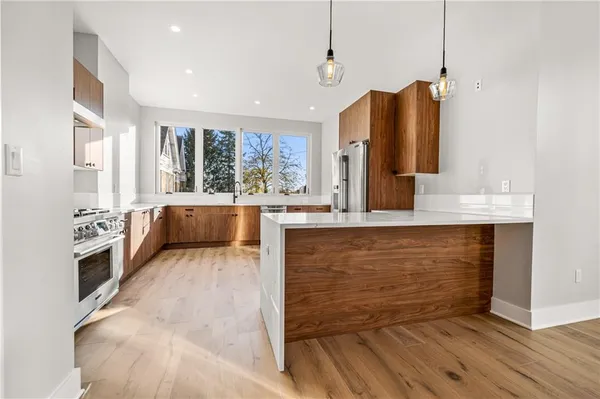 a large kitchen with stainless steel appliances granite countertop a stove a sink and a refrigerator