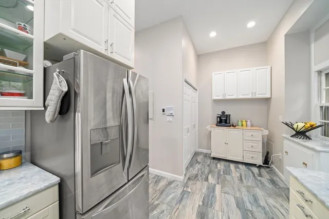 a kitchen with a refrigerator and white cabinets