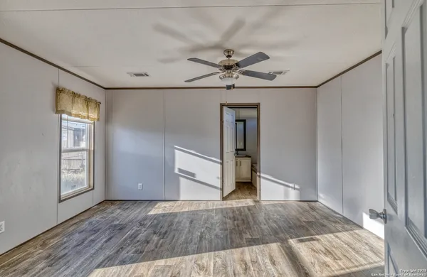 a view of empty room with wooden floor and fan