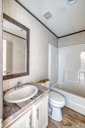 a bathroom with a granite countertop sink toilet a mirror and shower