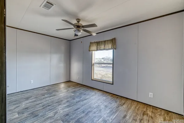 a view of an empty room with a window and wooden floor
