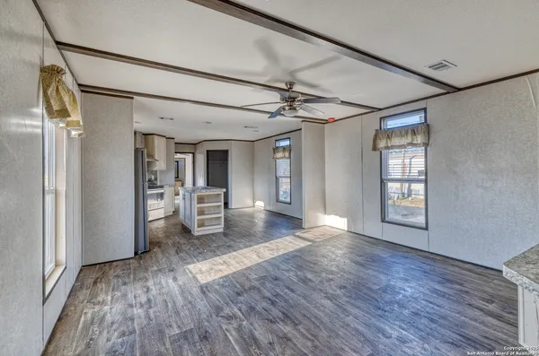 a view of a big room with wooden floor kitchen view and windows