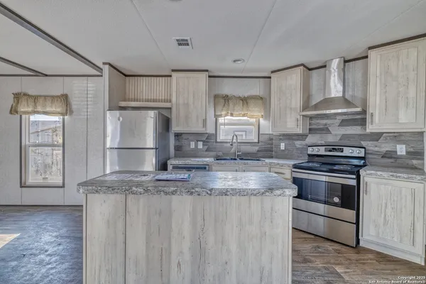 a kitchen with kitchen island granite countertop a sink stove and refrigerator