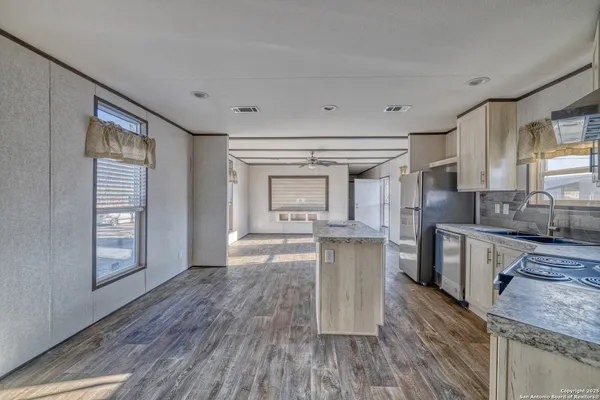 a kitchen with granite countertop a stove a sink and a refrigerator