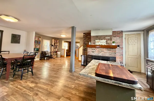 a kitchen with stainless steel appliances a refrigerator a sink dishwasher a stove top oven a dining table and chairs with wooden floor