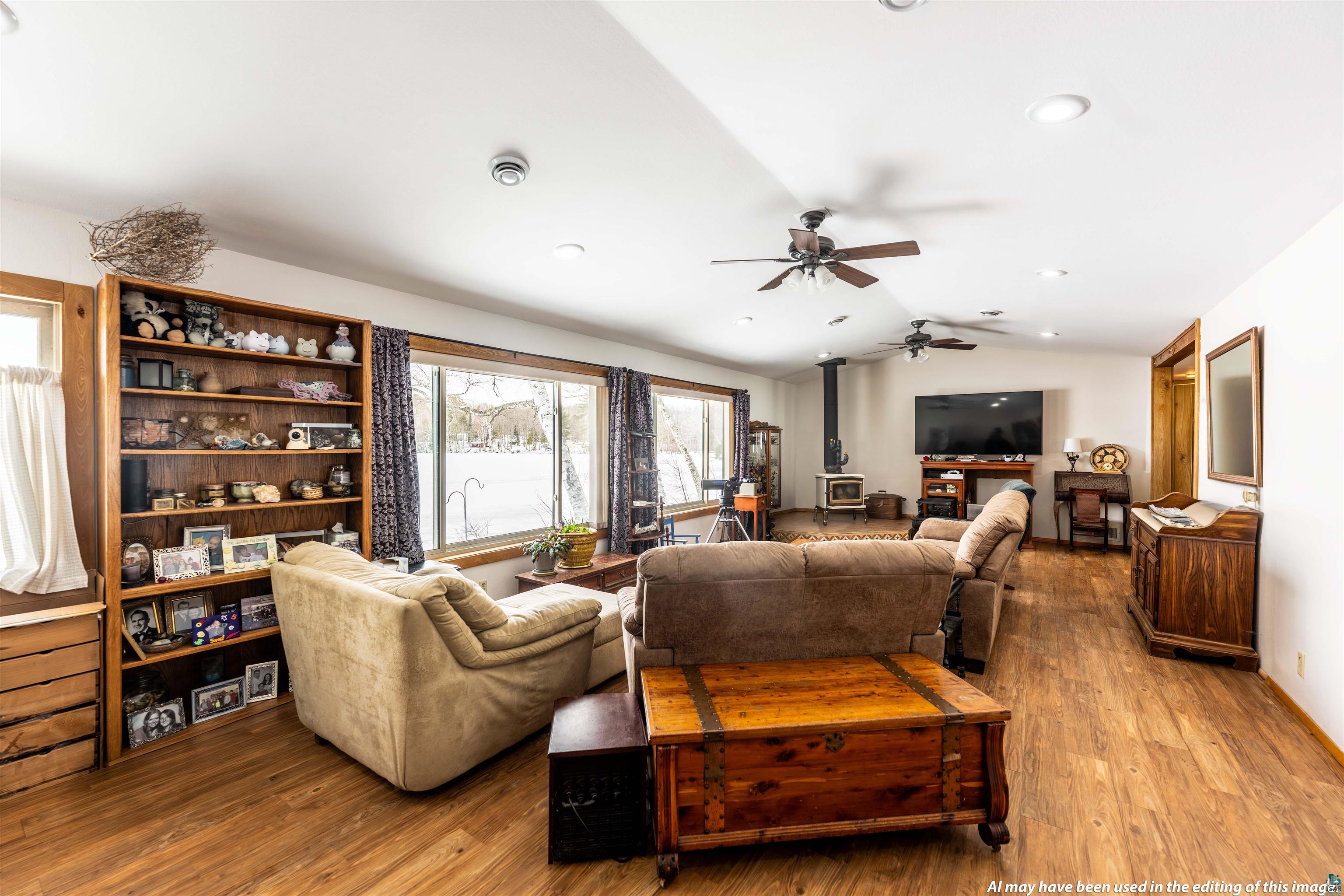 6030 Lake Ahmeek Road Hughes, WI 54847 - Photo 4 of 26 Living area with wood-type flooring, a wood stove, vaulted ceiling, and a ceiling fan