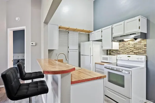 a kitchen with stainless steel appliances kitchen island a table chairs and a refrigerator