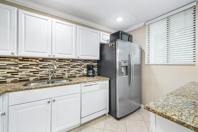 a kitchen with stainless steel appliances granite countertop a sink and a refrigerator