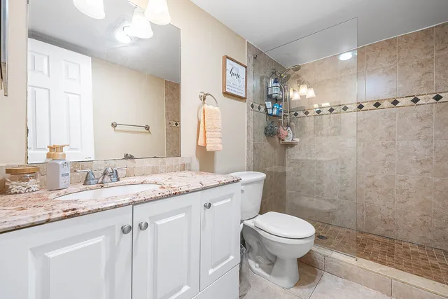 a bathroom with a granite countertop sink toilet a mirror a vanity and shower