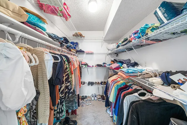 a view of walk in closet with clothes and shoes