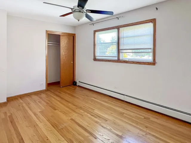 an empty room with wooden floor fan and windows