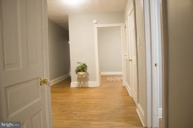 a view of a hallway with wooden floor and a dining room