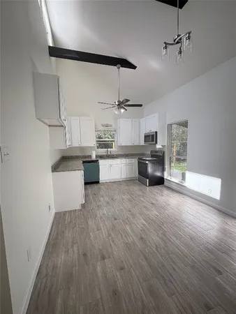 a large kitchen with cabinets wooden floor and stainless steel appliances