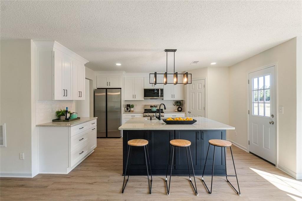 191 Kyndal Drive Hampton, GA 30228 - Photo 15 of 49 a kitchen with kitchen island a stove a table and chairs in it