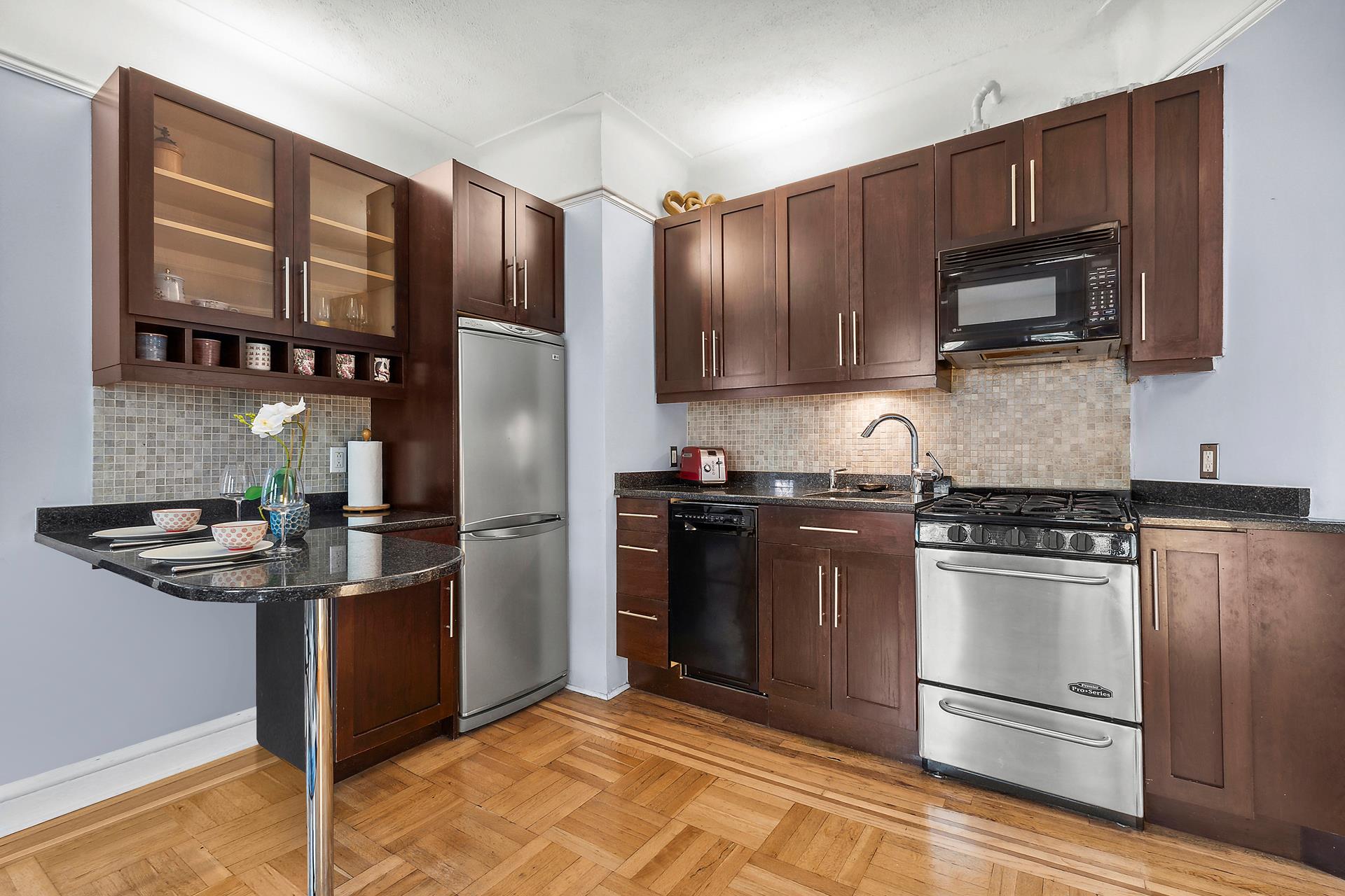 1-03 Minetta Street, Unit 5B Manhattan, NY 10012 - Photo 3 of 12 a kitchen with granite countertop stainless steel appliances and wooden cabinets