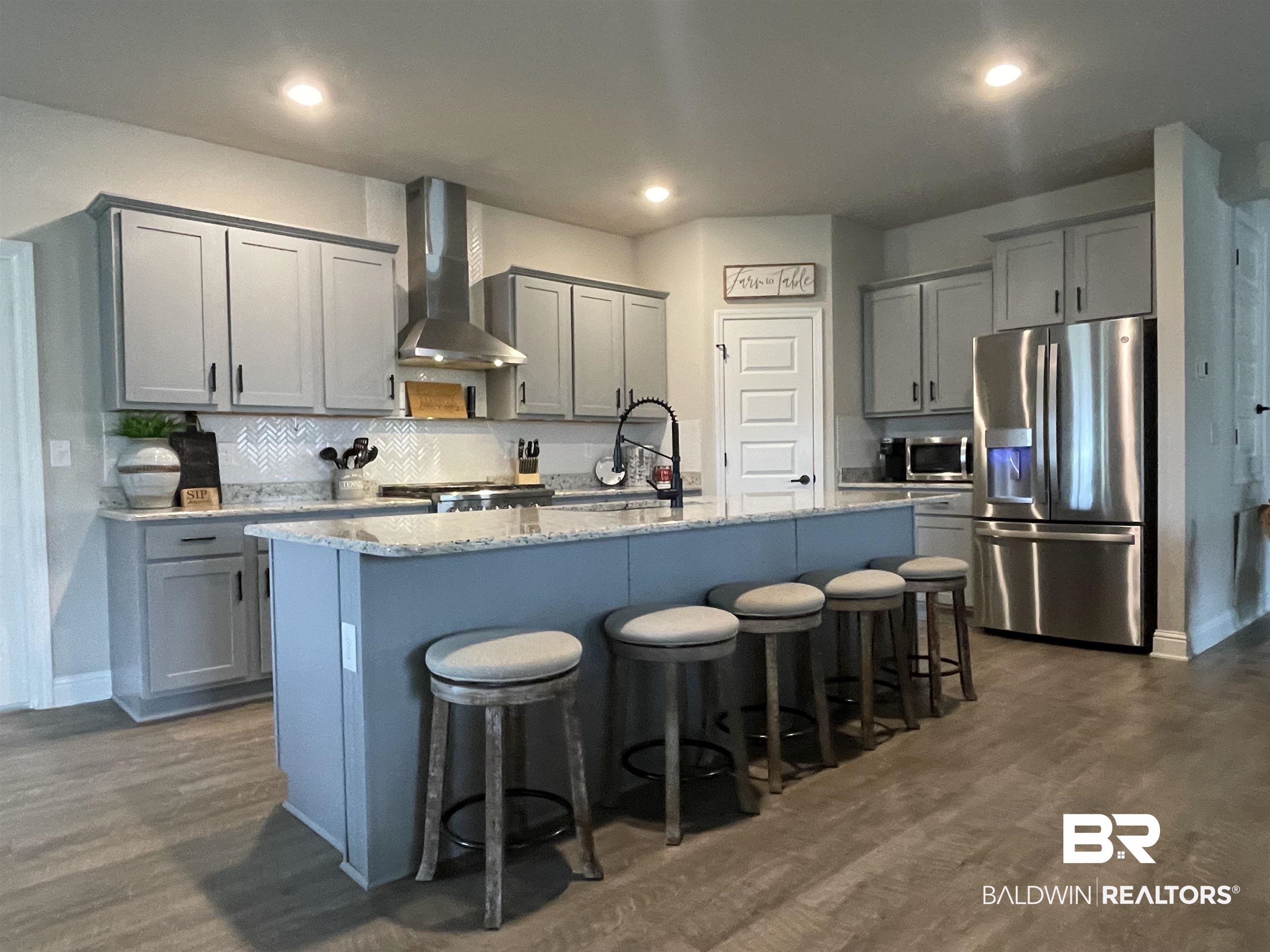 8621 Bronze Lane Foley, AL 36535 - Photo 5 of 13 Kitchen featuring wall chimney range hood, dark wood-type flooring, an island with sink, stainless steel appliances, and gray cabinetry