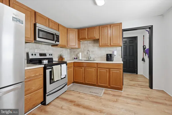 a kitchen with stainless steel appliances granite countertop a stove top oven a sink dishwasher and a refrigerator with wooden floor