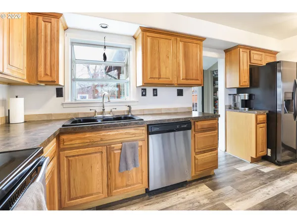 a kitchen with stainless steel appliances granite countertop a refrigerator a sink dishwasher and wooden cabinets