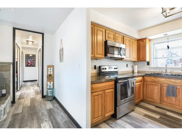 a kitchen with stainless steel appliances granite countertop a stove top oven a sink dishwasher and a refrigerator with wooden floor