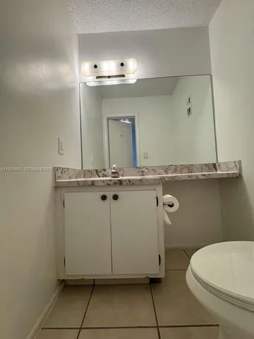 a bathroom with a granite countertop sink a toilet and mirror