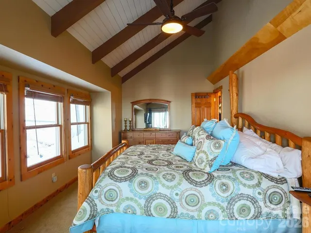 a bedroom with a bed next to a window with wooden floor