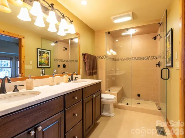 a bathroom with a double vanity sink toilet mirror and shower