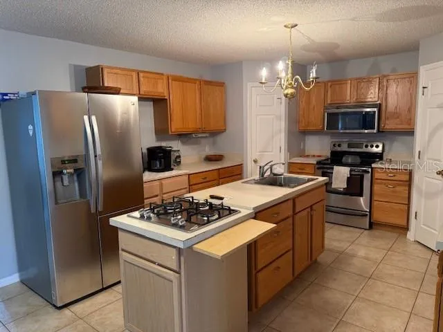 a kitchen with stainless steel appliances granite countertop a stove refrigerator sink and microwave